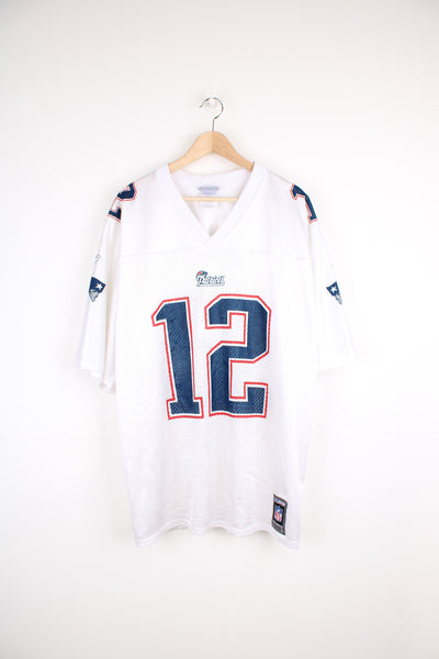 Vintage New England Patriots NFL Reebok Jersey in a white, blue and red colourway, Tom Brady number 12 jersey, v neck, and has the logos and numbers printed on the front, back and both sleeves.