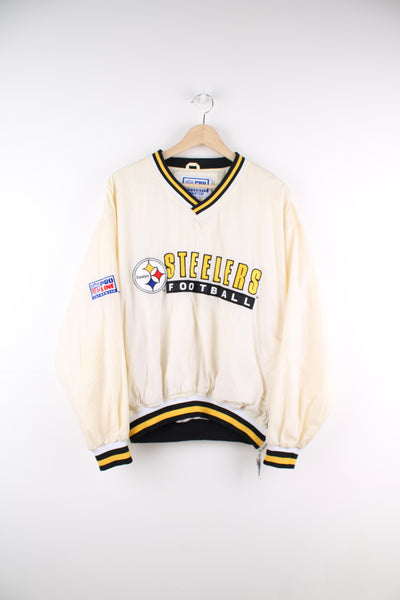 Vintage Pittsburg Steelers cream/off white nylon pullover training top by Starter with embroidered spell-out details across the chest and logo on the cuff